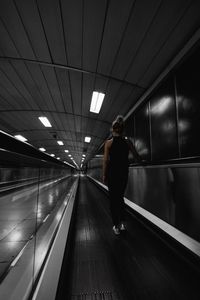 Rear view of woman walking on illuminated corridor