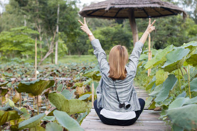 Asian woman raising her hands on a wooden bridge