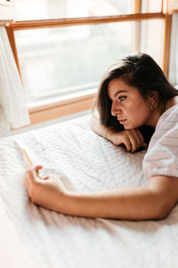 Portrait of woman lying on bed at home