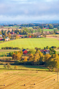 Scenic view of agricultural field by buildings against sky