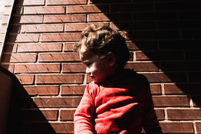 Boy looking at camera on staircase against brick wall