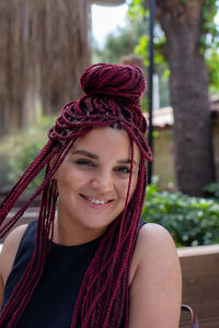 Portrait of smiling young woman with red dreadlocks sitting at outdoor cafe. diverse concept person