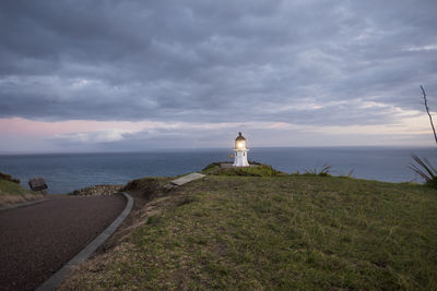 Lighthouse by sea against sky