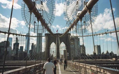 Low angle view of suspension bridge against cloudy sky