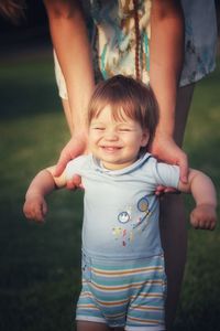 Baby boy with blonde hair  smiling when making first steps in parent arms