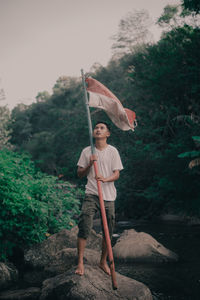 A young man is lifting the red and white flag of the indonesian nationality