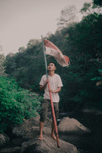 Full length of man standing on rock against trees