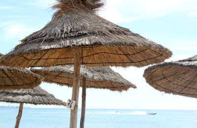 Low angle view of beach umbrella by sea against sky