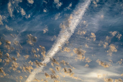 Blue sky covered in small clouds and a diagonal plane trail