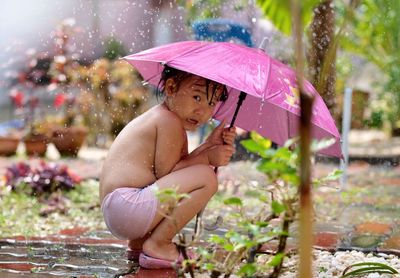 Portrait of cute girl with umbrella during rainy season