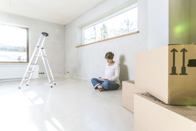 Pregnant woman using digital tablet while sitting at home