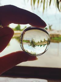 Close-up of hand holding glass with reflection