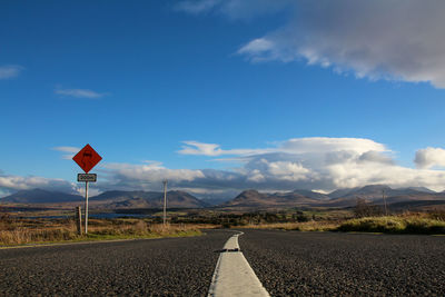 Road sign against cloudy sky