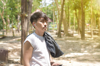 Side view of young man standing in forest