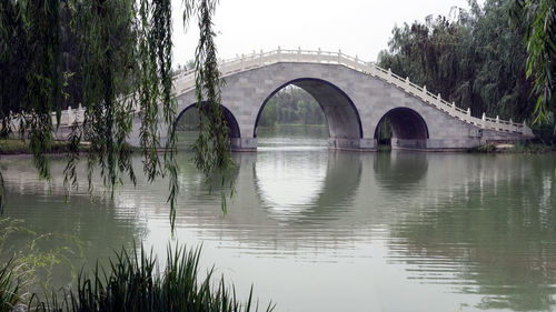 Arch bridge over lake against sky