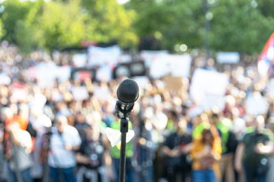 Focus on microphone, blurred group of people at mass protest in the background