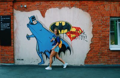 Full length of woman with graffiti on wall