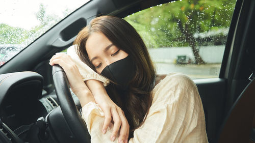 Close-up of woman wearing mask sitting in car