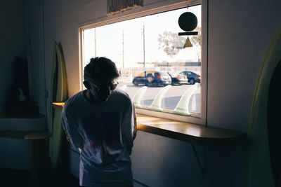 Man wearing sunglasses standing by window