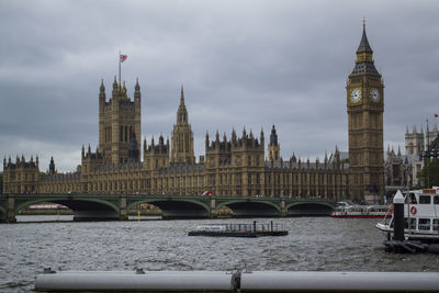 Bridge over river in city against cloudy sky