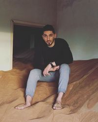 Portrait of young man sitting on floor at home