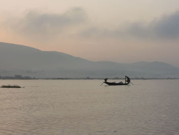 Silhouette boat in lake against sky 