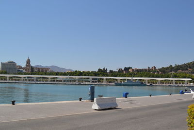 Swimming pool by sea against clear blue sky