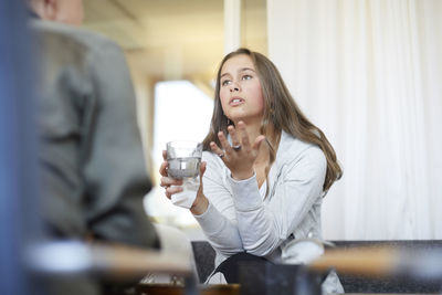 Depressed teenager talking to therapist while drinking water at workshop