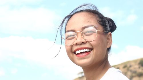 Portrait of smiling young woman against sky