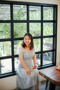 Portrait of young woman looking through window