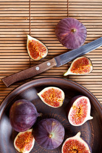 Plate with fresh figs and old knife on straw background