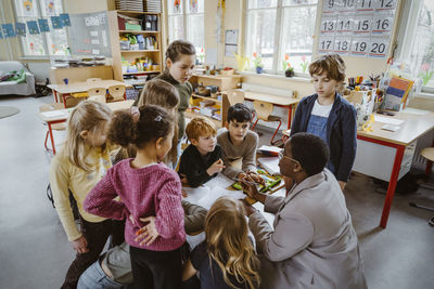 Teacher assisting boys and girls in classroom at elementary school