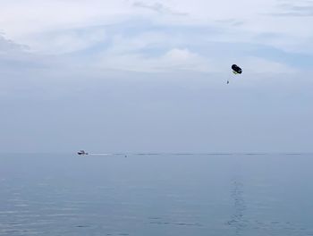 Kite flying over sea against sky