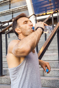 Midsection of shirtless man standing against the wall