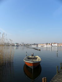 Sailboats moored in lake against sky