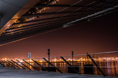 Illuminated bridge over river against sky at night