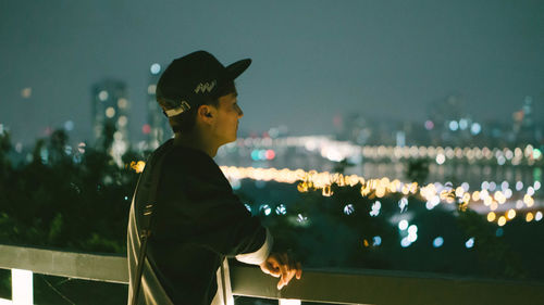 Young woman sitting against illuminated sky at night