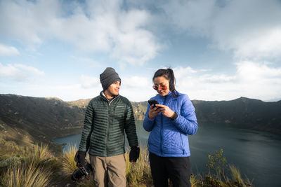 Couple taking photos in the mountains with lake behind