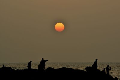 Silhouette people on beach against sky at night