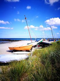 Sailboats moored on beach against sky