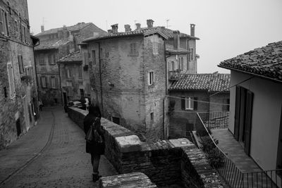 Rear view of woman standing on road amidst buildings in city