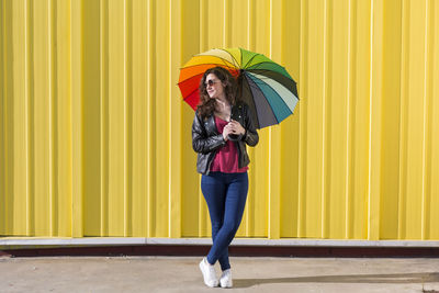 Full length of a woman standing on yellow umbrella