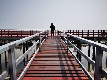 Rear view of man standing on footbridge