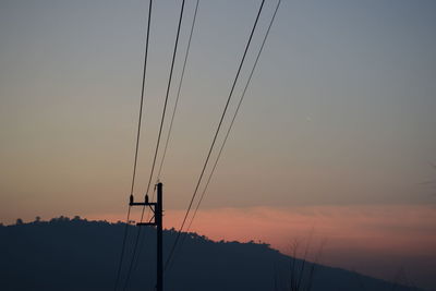 Low angle view of silhouette electricity pylon against sky during sunset