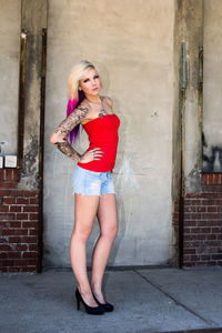 Portrait of young woman standing on wall