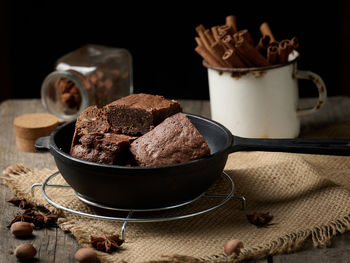 Pieces of baked brownie in a metal black frying pan on the table