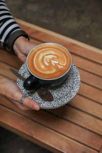 Cropped hand of woman holding coffee on table