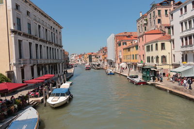 Boats in canal amidst buildings in city against sky