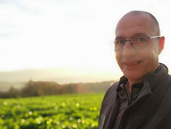 Portrait of smiling man standing on field against sky