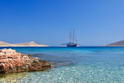 Sailboat in sea against clear blue sky